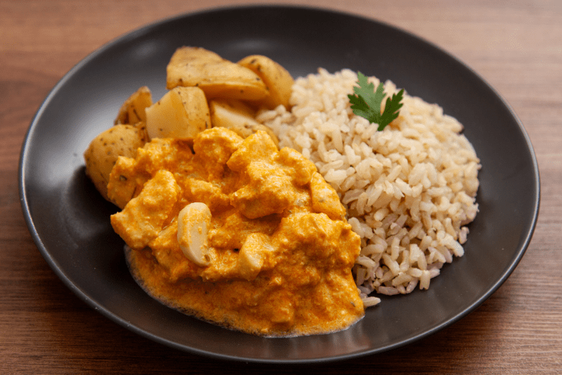 Prato de strogonoff de frango cremoso servido com arroz branco e batata palha crocante.