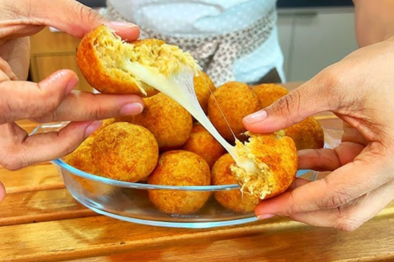 Bolinhas douradas de frango com batata e queijo servidas em um prato rústico, acompanhadas de molho.