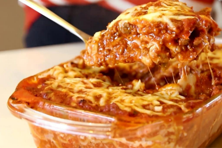 Lasanha de carne cremosa e gratinada, servida em uma travessa branca, com queijo derretido e manjericão fresco, perfeita para almoços e jantares especiais.