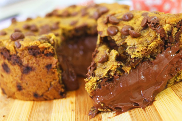 Torta Cookie dos Sonhos, recheada com creme de avelã e coberta com gotas de chocolate, sobre uma mesa de cozinha.