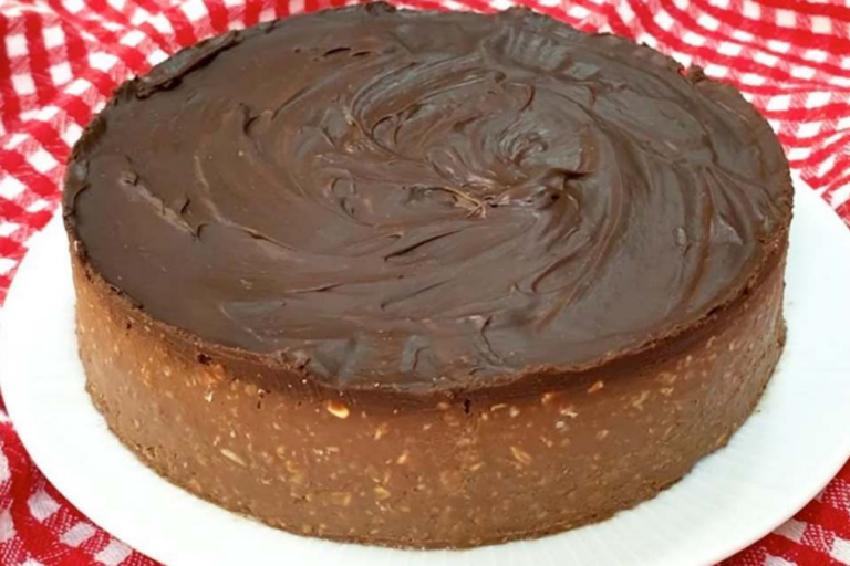 Uma deliciosa torta de chocolate cremosa servida em um prato, com cobertura brilhante e raspas de chocolate por cima.