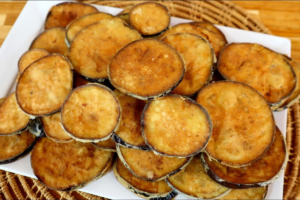 Rodelas de berinjela empanadas, douradas e crocantes, servidas em prato rústico com molho de acompanhamento ao lado