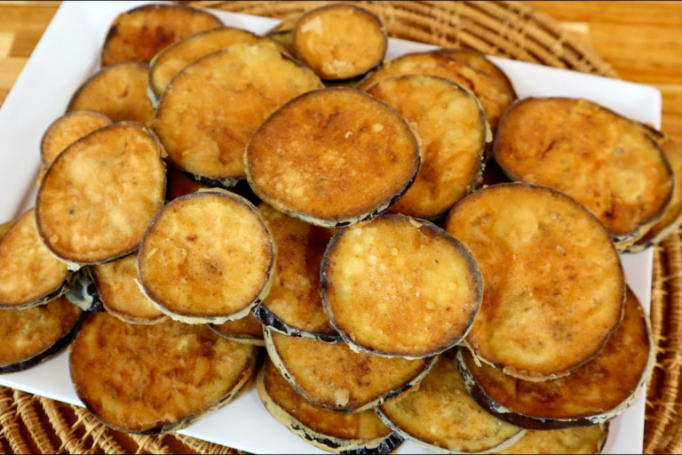 Rodelas de berinjela empanadas, douradas e crocantes, servidas em prato rústico com molho de acompanhamento ao lado